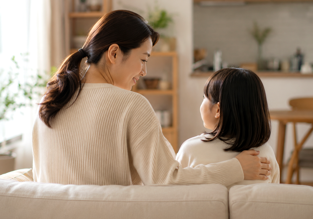 소파에 나란히 앉아 아이를 안아주며 정서적으로 지지하는 엄마와 여자아이