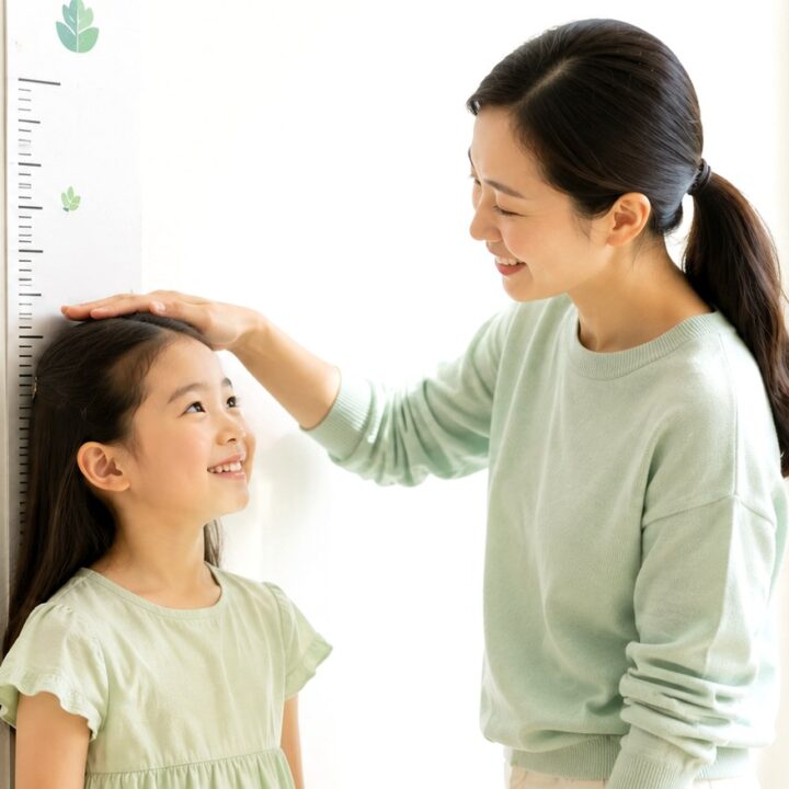 구미 소아 성조숙증 – 벽 키재기 자 앞에서 키를 재는 아이와 엄마